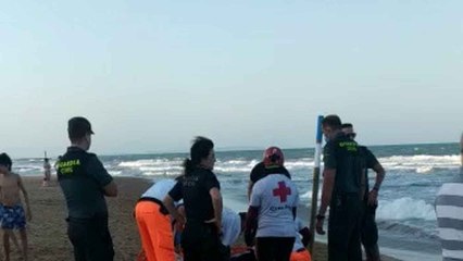 Personal sanitario asistiendo sobre la arena a uno de los rescatados