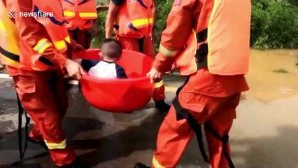 Firefighters use basin to transport sick nine-month-old to hospital through deep floodwater