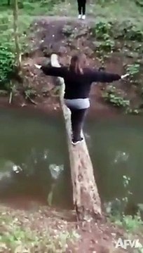 cette femme réussit à traverser un cours d’eau sur un tronc d’arbre, mais une fois sur la terre, elle a glissé et tombe finalement dans l’eau