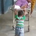 A six-year-old boy pushes a stretcher along with his mother to take his ailing grandfather from one ward to another