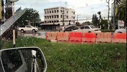 Traffic barriers float down road during flash floods in Thailand