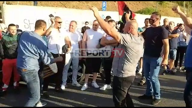 Report TV -Qindra kosovarë presin kthimin e Thaçit nga Haga me flamujt e UÇK-së, këngë e valle