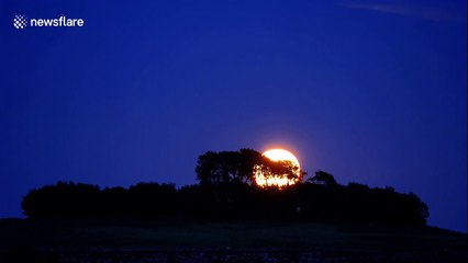 Full 'Sturgeon Moon' rising over Peak District National Park in central England