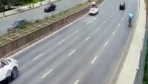 Chinese men sit on car roof as it drives along road
