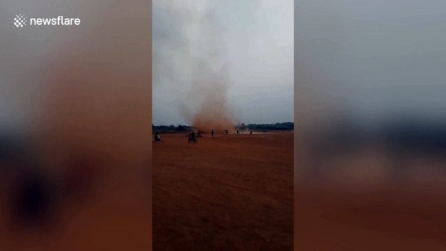 Fearless children run through deep red dust devil tornado in Indonesia