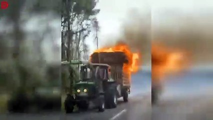 Ce tracteur roule tranquillement sur la route avec sa remorque en feu