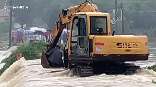 Firefighters use excavator to rescue three-wheeler driver trapped on flooded bridge