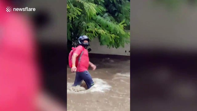 Residents wade through flooded roads in Delhi, India