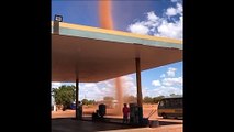 Une mini tornade de sable passe juste à côté d'une station essence