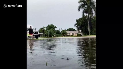 Father-son duo create waves to surf on flooded Florida street