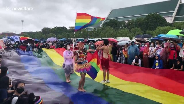 Thai protesters wave LGBT flag at anti-government rally during heavy rain