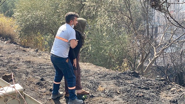 Yanan evine koşmaya çalışan kadını görevliler zor tuttu