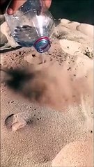 Il verse de l'eau sur le sable, ce qui se passe est incroyable