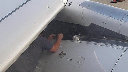 Un technicien fait une réparation au scotch sur un réacteur d'avion