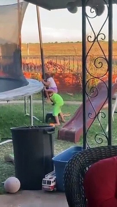 Il aide sa petite sœur à monter sur un trampoline