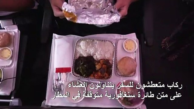 ركاب متعطشون للسفر يتناولون العشاءعلى متن طائرة سنغافورية متوقفة في المطار