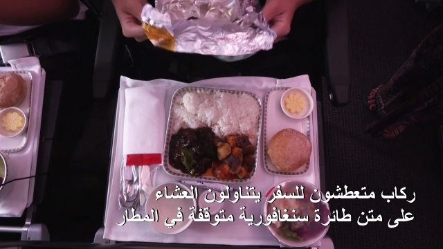 ركاب متعطشون للسفر يتناولون العشاءعلى متن طائرة سنغافورية متوقفة في المطار