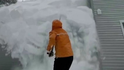 Snow races down roof onto woman