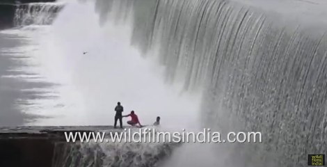 Three men take photographs in front of flooding Chandauli dam in North India