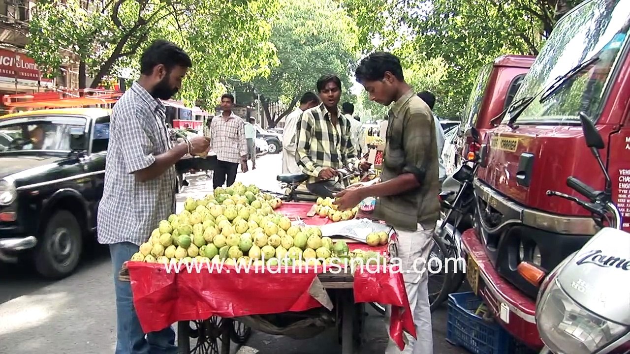 Mumbai street vendor with cart full of ripe Guavas - Customers, pedestrians and Fiat Padmini taxis