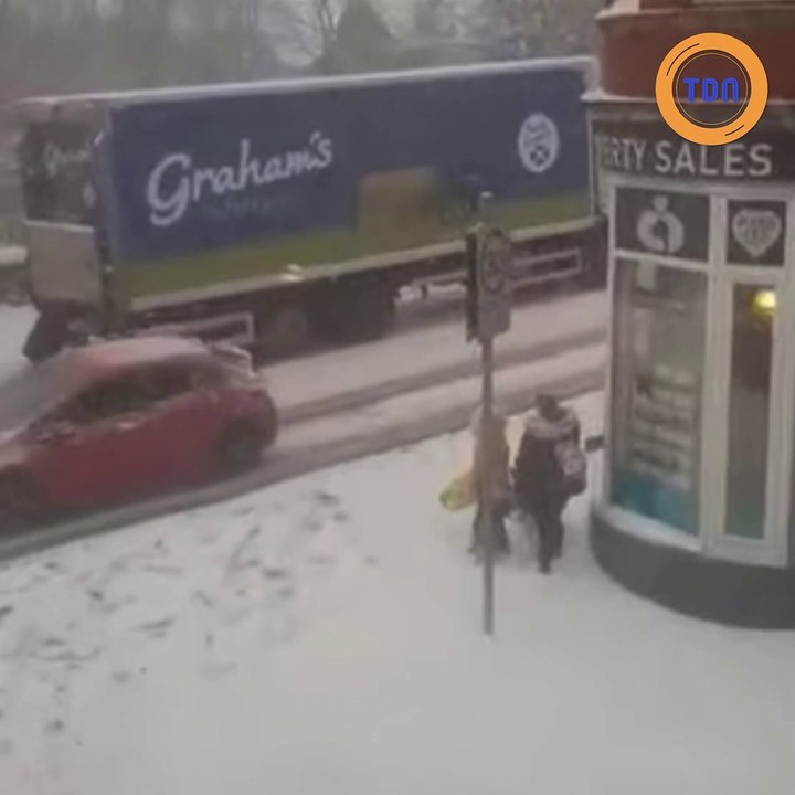 Une mère de famille pousse un camion coincé dans la neige