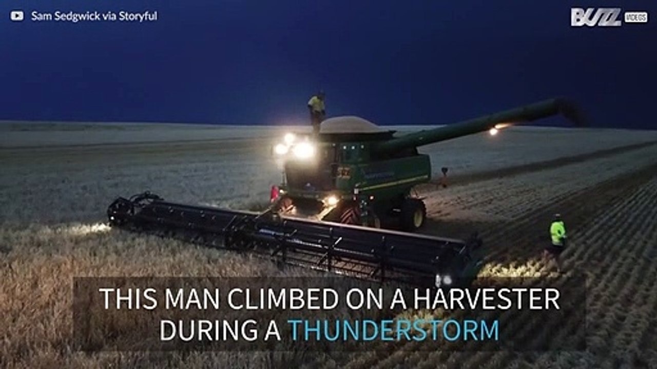 Man dances on top of combine harvester during thunderstorm