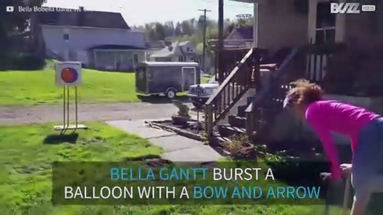 Girl pops a balloon with a bow and arrow...while doing a handstand!