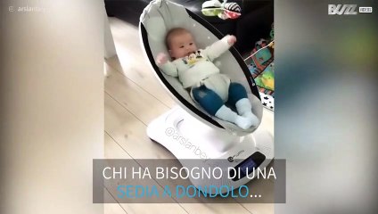 Bebè si diverte da solo sulla sedia a dondolo