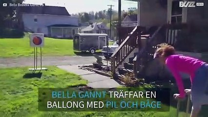Flicka smäller en ballong med pil och båge...samtidigt som hon står på händerna!