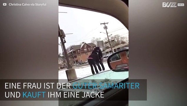Eine Frau gibt einem Mann einen Mantel, nachdem sie ihn in der Kälte sieht.