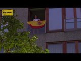 Els manifestants ignoren a una senyora que llueix eufòricament la bandera espanyola al seu balcó