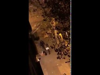 Un policia dispara un tret de foam al costat d'un ferit que està al terra