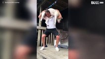 Man doet squats met een gigantische hond op zijn rug