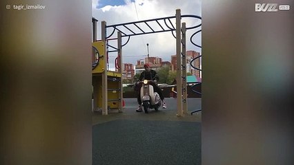 Jovem faz elevações na barra com uma mota atrelada no corpo