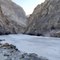 Person Sits Beside Frozen River In Ladakh In India