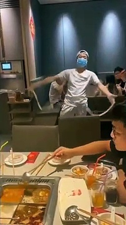 Enthusiastic restaurant worker dances while pulling one-strand noodle in Vietnam