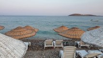 Lines Of Beach Chairs Shaded By Rattan Umbrellas On The Shore Of A Beach