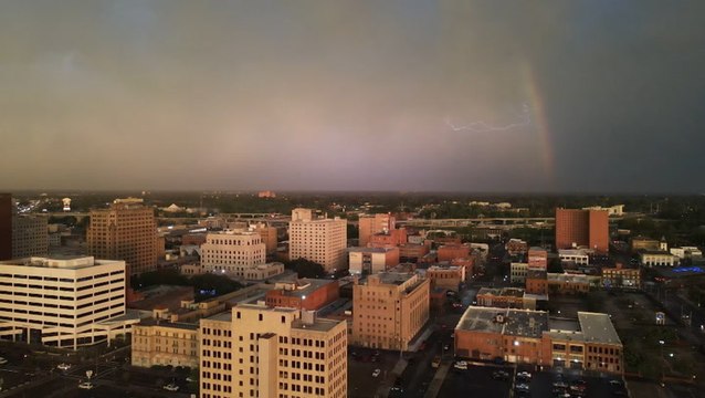 Lightning streaks across the sky behind a rainbow