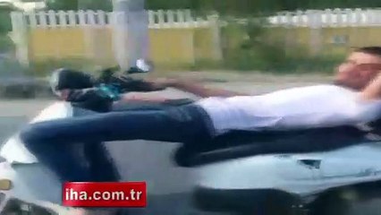 Koltuğuna sırt üstü yattığı motosikleti tek elle kullandı