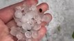 Person Moves Hand Through Pile of Hailstones in Driveway to Show Outcome of Hailstorm