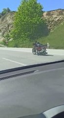 Üzerine uzandığı motosikletle tehlikeli yolculuk