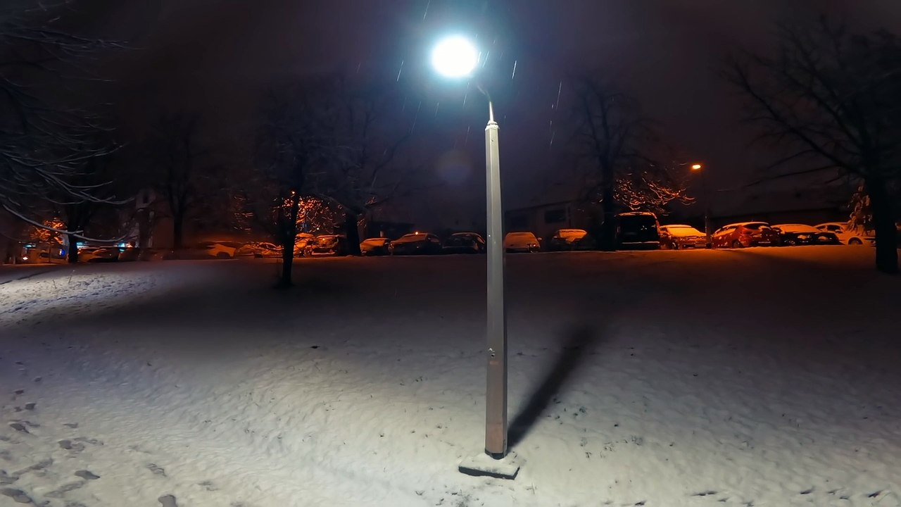 A lonely street lamp standing in park during snowy winter night.