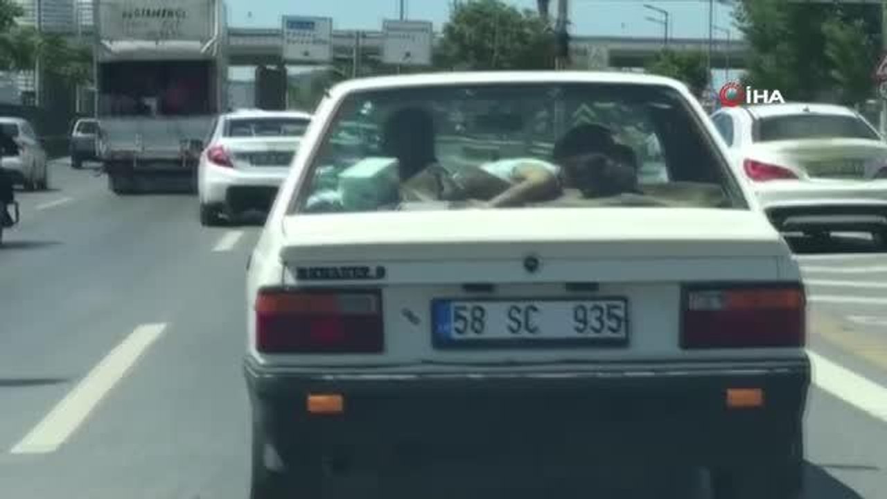 Trafikte ilginç görüntü: Uyuyan çocuğu arabanın arka camına yatırdı