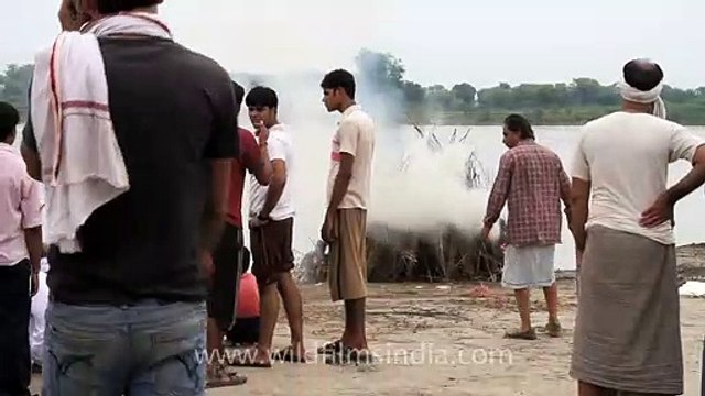 People watch while a dead person burns_ Hindu cremation ceremony, Vrindavan