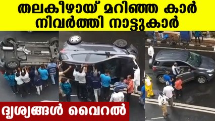 People helping overturned car back to it's wheel