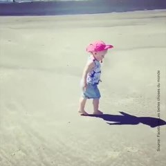 Un bébé joue avec son ombre sur la plage