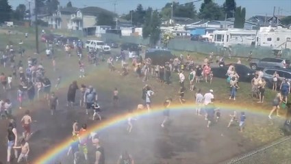 Rainbow pops out as fire crews spray crowds to keep cool