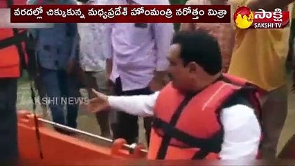 వరదల్లో చిక్కుకున్న హోం మంత్రి.. తాడు కట్టి పైకి లాగారు