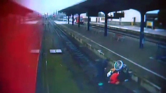 Homem empurra mulher em cadeira de rodas para a linha de comboio