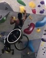 Un homme en fauteuil roulant grimpe ce mur d'escalade avec facilité